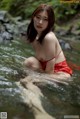 A woman in a red bikini is sitting in the water.