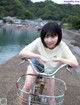 A young woman riding a bike with a basket on the back.